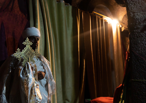 Portrait of an ethiopian orthodox priest holding a cross inside a rock-hewn church, Amhara Region, Lalibela, Ethiopia