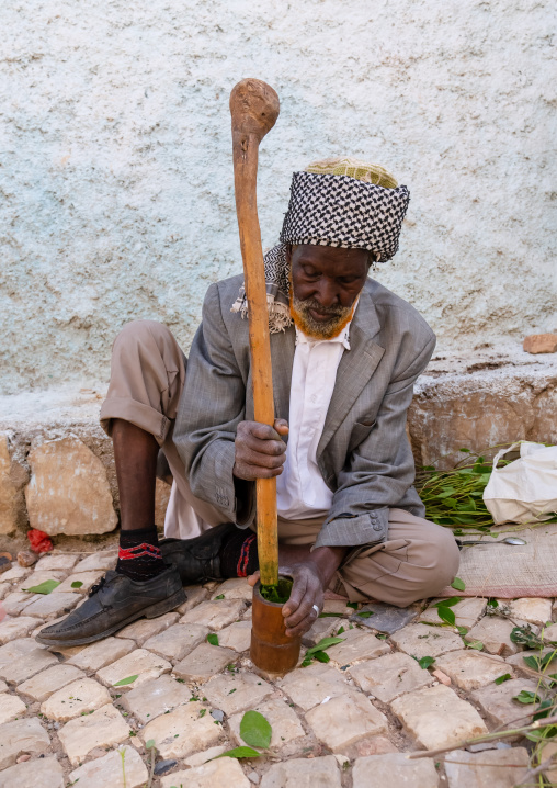 Old man without teeth crashing qat to chew In the street, Harari Region, Harar, Ethiopia