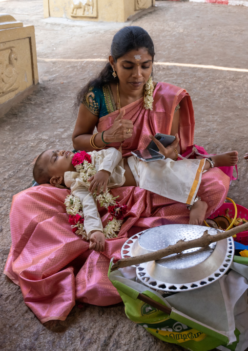 Indian mother texting in a temple with her child, Tamil Nadu, Chettinad, India