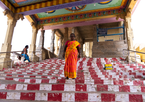 Indian woman on a red and white stairs in a temple, Tamil Nadu, Chettinad, India