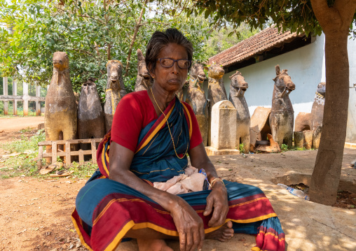 Indian woman in front of terracotta Horses in a temple, Tamil Nadu, Karaikudi, India