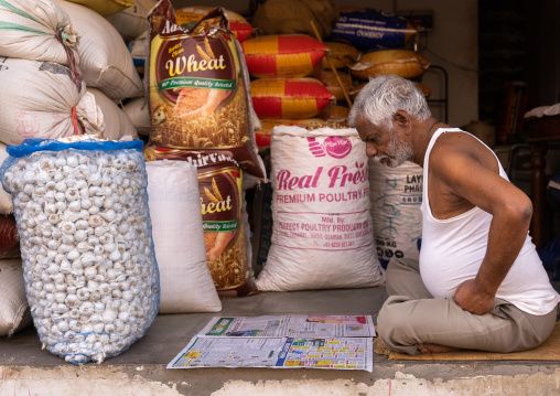 Old indian man reading newspaper in his shop, Rajasthan, Ramgarh Shekhawati, India