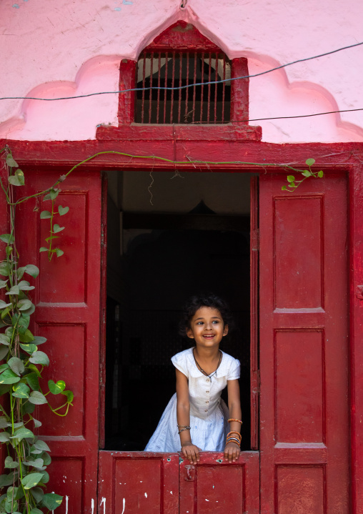 Indian girl standing in a red door in old Delhi, Delhi, New Delhi, India