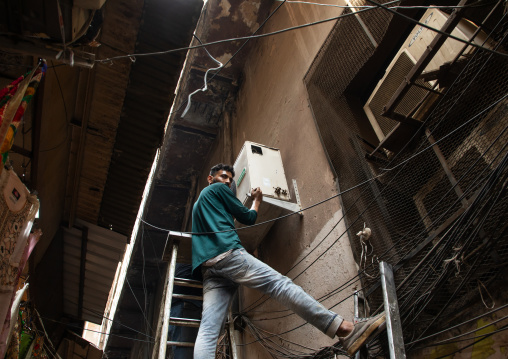Indian man installing air conditioners in old Delhi, Delhi, New Delhi, India