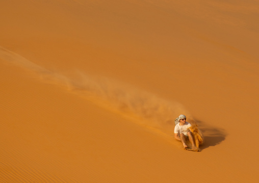 Tourist making sandboarding in the Rub al Khali dunes desert, Najran Province, Thar, Saudi Arabia