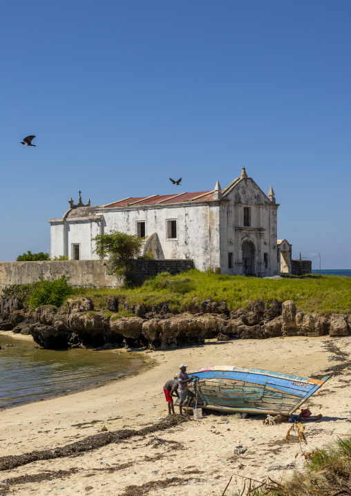 Men fixing a boat in front of the Chapel of Santo Antonio, Nampula Province, Island of Mozambique, Mozambique