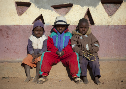 Himba Kids Dressed In A Western Way Sitting On A Bench, Village Of Oncocua, Angola