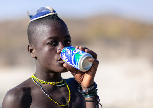 Himba tribe young man drinking a Sprite, Cunene Province, Oncocua, Angola