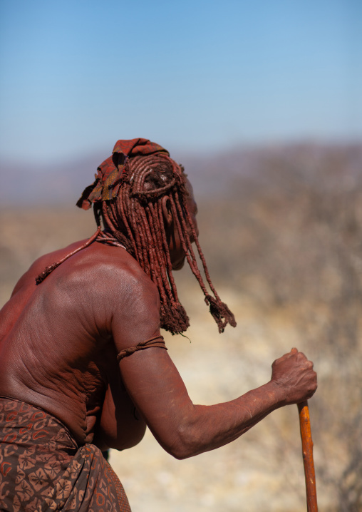 Old Himba tribe woman walking with a stick, Cunene Province, Oncocua, Angola