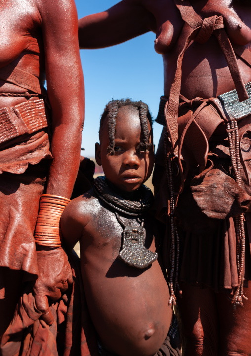 Himba tribe girl between two adults, Cunene Province, Oncocua, Angola