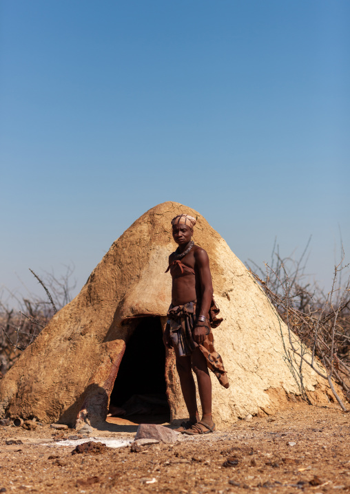 Himba tribe man standing in front of his mud hut, Cunene Province, Oncocua, Angola