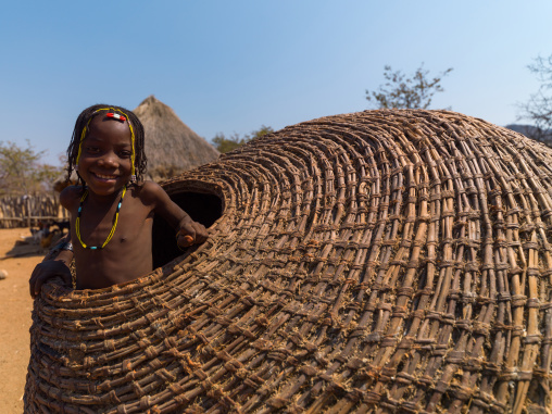 Muhacaona tribe girl inside a giant basket used to keep the corn, Cunene Province, Oncocua, Angola