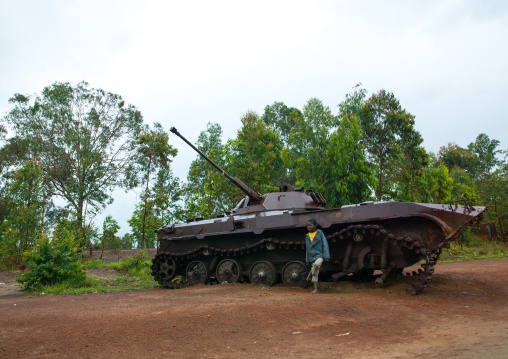 Angolan child standing in front of an old tank from the civil war, Bié Province, Kuito, Angola