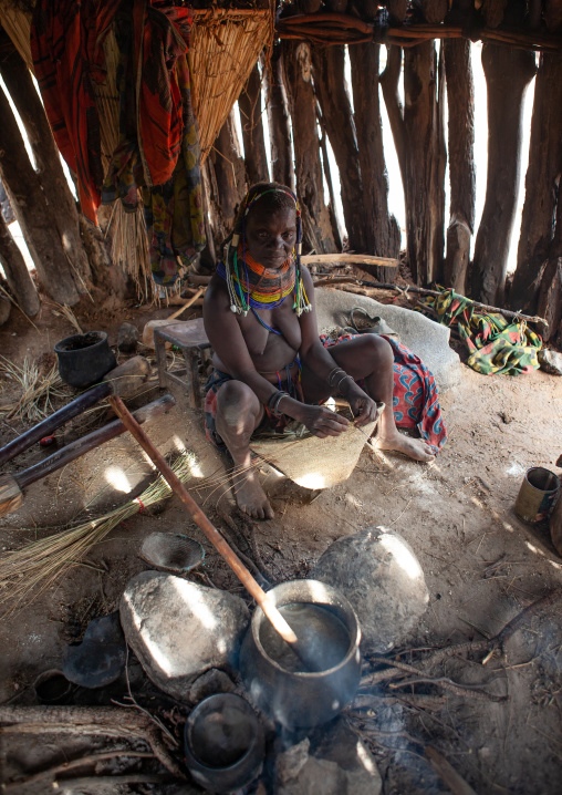 Mumuhuila tribe woman cooking inside her hut, Huila Province, Chibia, Angola