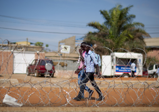 Angolan Teenagers Walking Next To Barbed Wire, Luanda, Angola