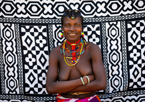 Portrait of a smiling mudimba tribe woman in front of a printed cloth, Cunene Province, Cahama, Angola