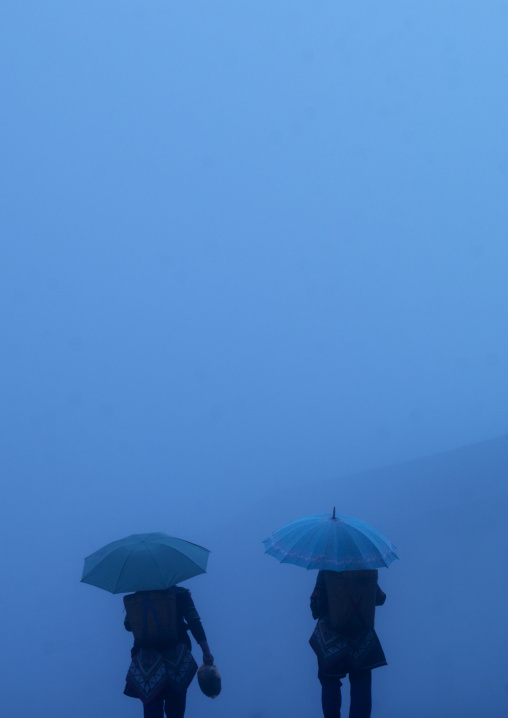 Two Women With Umbrella Walking In The Fog, Yuanyang, Yunnan Province, China