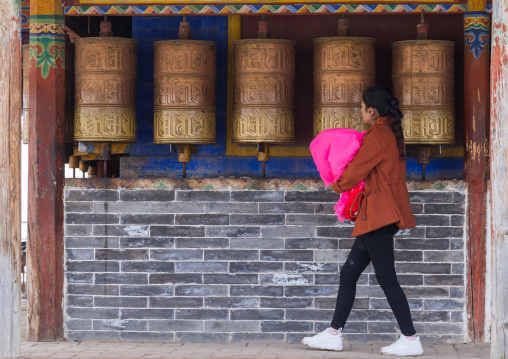 Tibetan pilgrim woman turning prayer wheels in Shachong monastery, Qinghai Province, Wayaotai, China