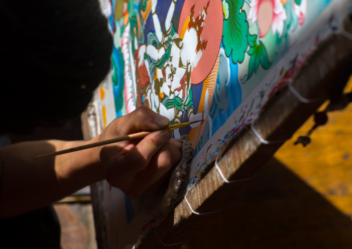 Tibetan artist painting a thangka at a workshop, Qinghai province, Wutun, China