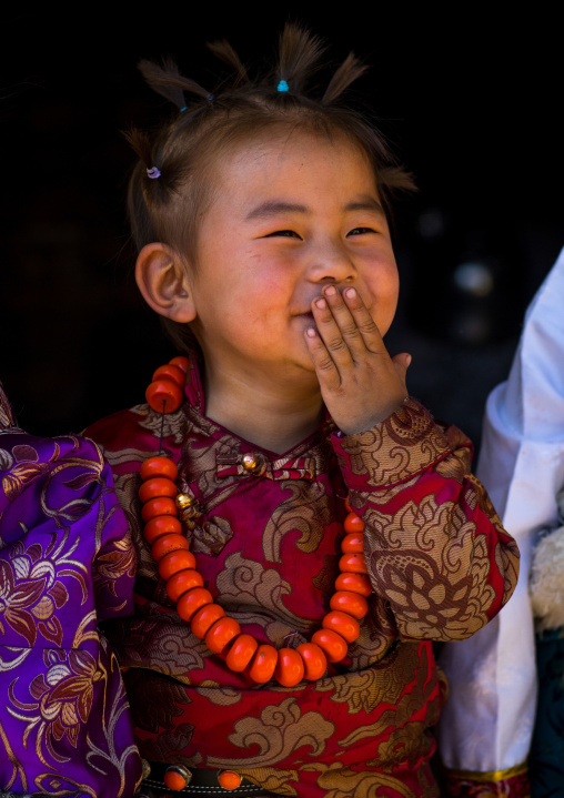 Laughing tibetan child girl with a huge necklace, Tongren County, Rebkong, China