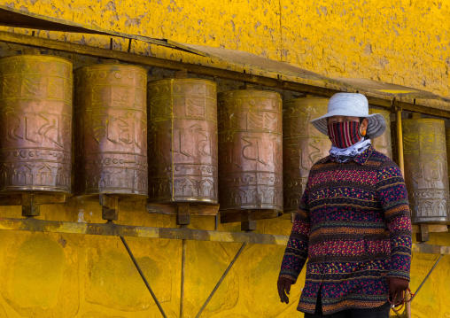 Tibetan pilgrim turning huge prayer wheels in Rongwo monastery, Tongren County, Longwu, China