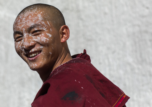tibetan Monk with white painting on his face while renovating the walls of a temple in Rongwo monastery, Tongren County, Longwu, China