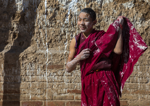 Tibetan monk enjoying a water fight after the yearly renovation of the Rongwo monastery, Tongren County, Longwu, China
