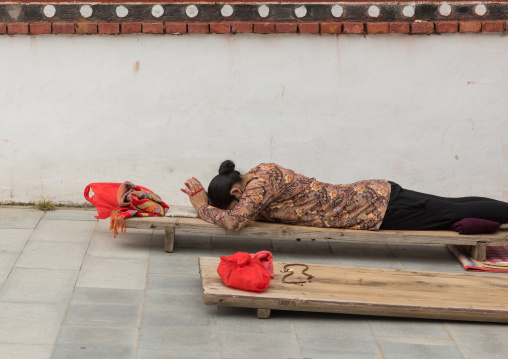 Tibetan pilgrim woman praying and prostrating in Hezuo monastery, Gansu province, Hezuo, China