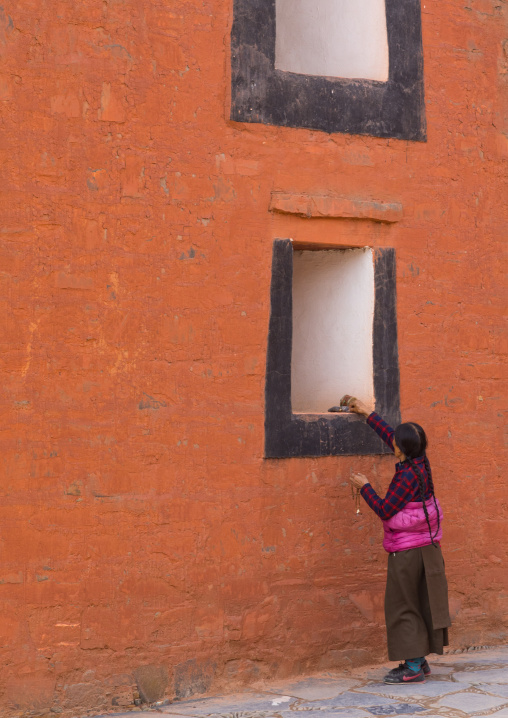 Tibetan pilgrim woman putting a donation on a temple window in Labrang monastery, Gansu province, Labrang, China