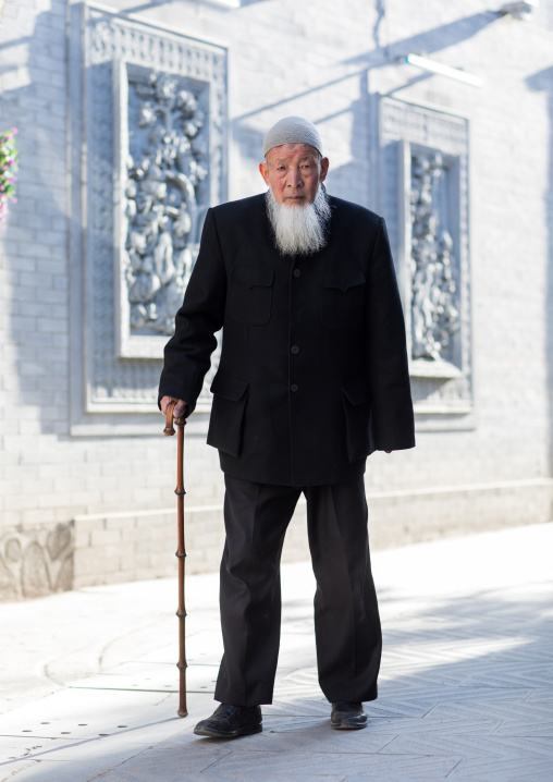 Hui muslim man walking with cane in the street, Gansu province, Linxia, China
