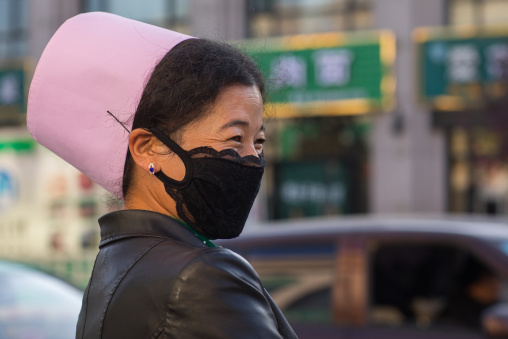 Muslim woman with the traditional pink hat and a mask in the street, Gansu province, Linxia, China