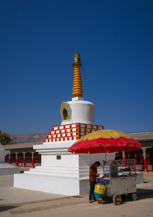 Woman selling food in front of a stupa in Wutun si monastery, Qinghai province, Wutun, China