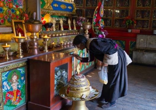 Tibetan woman praying inside a temple of Rongwo monastery, Tongren County, Longwu, China