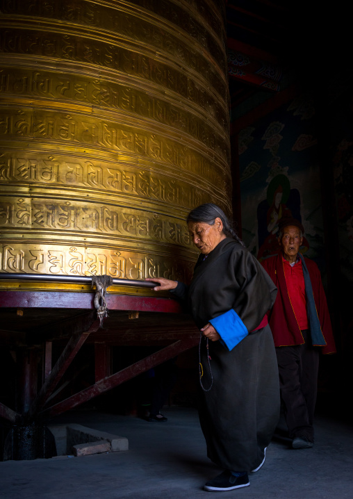 Tibetan pilgrims turning huge prayer wheel in Rongwo monastery, Tongren County, Longwu, China