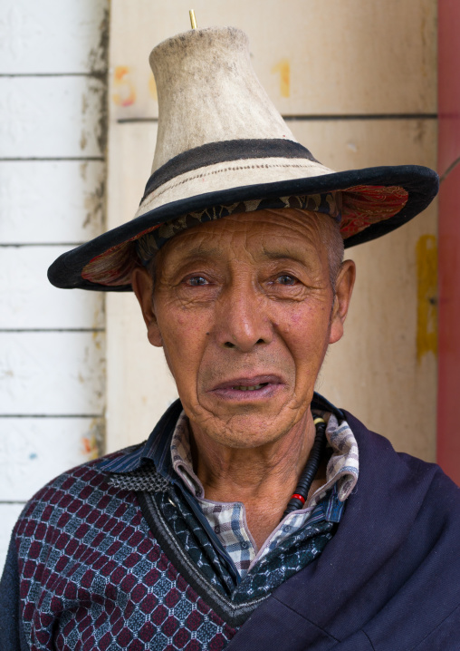 Portrait of an old tibetan man with a traditional and conical hat, Tongren County, Longwu, China
