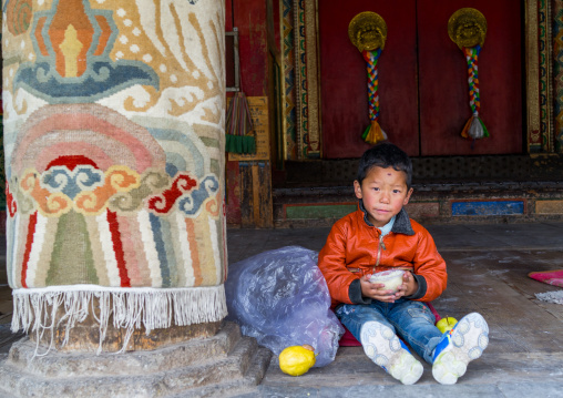 Tibetan boy eating in Rongwo monastery, Tongren County, Longwu, China