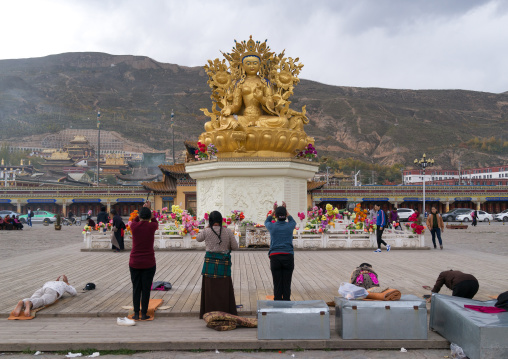 Tibetan people praying in front of the  statue of the buddhist goddess tara outside longwu monastery, Tongren County, Longwu, China
