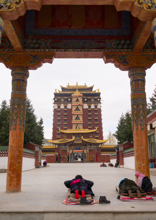 Tibetan pilgrims praying and prostrating in front of Hezuo monastery and its milarepa tower, Gansu province, Hezuo, China