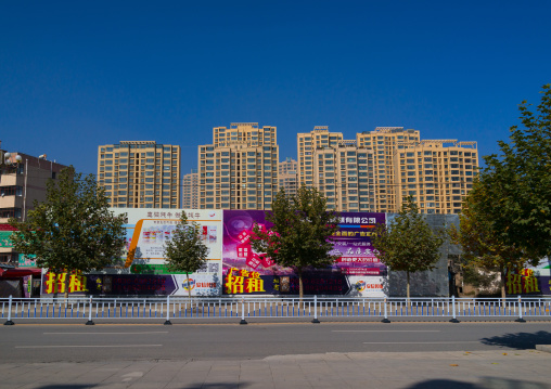 Huge advertising billboards in front of new hirise buildings, Gansu province, Linxia, China