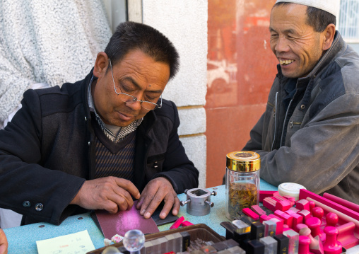 Carver making traditional chinese stamp in the street, Gansu province, Linxia, China