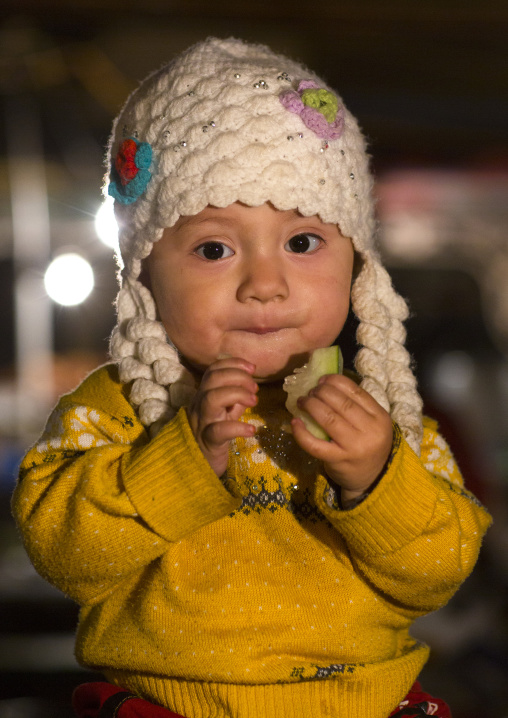 Uyghur Baby Eating A Piece Of Fruit, Night Market, Hotan, Xinjiang Uyghur Autonomous Region, China