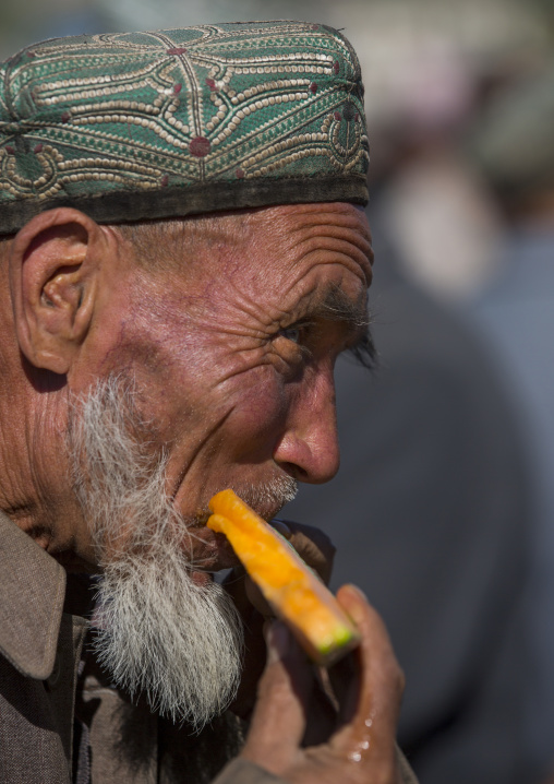 Uyghur Man eating fruit In Kashgar Animal Market, Xinjiang Uyghur Autonomous Region, China