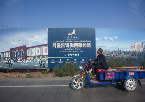 old man passing in front of Advertisement For New Real Estate, New Town Of Kashgar, Xinjiang Uyghur Autonomous Region, China