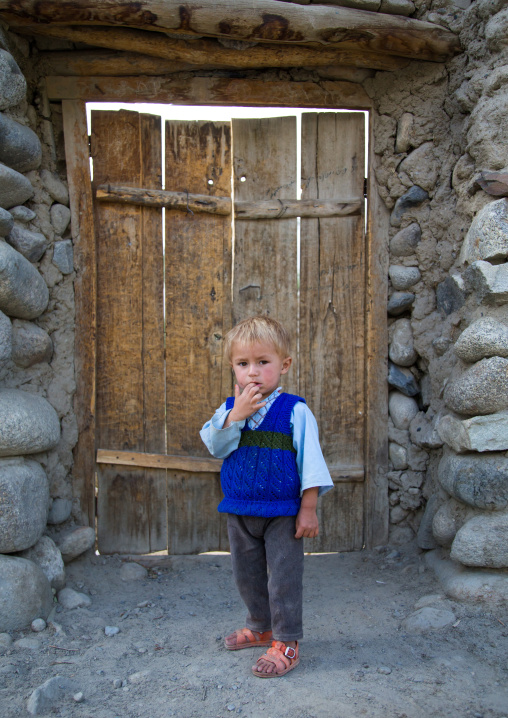 Afghan boy with blonde hair in front of a wooden door, Badakhshan province, Khandood, Afghanistan