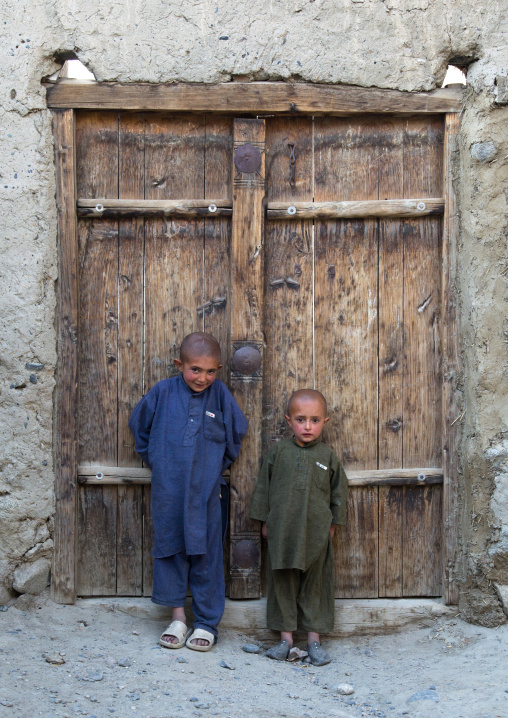 Afghan boys with shaved heads standing in front of a wooden door, Badakhshan province, Khandood, Afghanistan