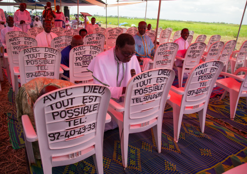 Benin, West Africa, Ganvié, celestial church of christ men praying in front of a chair with "with god everything is possible" slogan