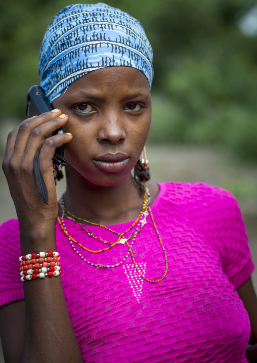 Benin, West Africa, Gossoue, a beautiful tattooed fulani peul tribe woman pausing with her mobile phone