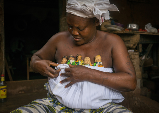 Benin, West Africa, Bopa, miss ablossi carrying the carved wooden figures of her five dead twins