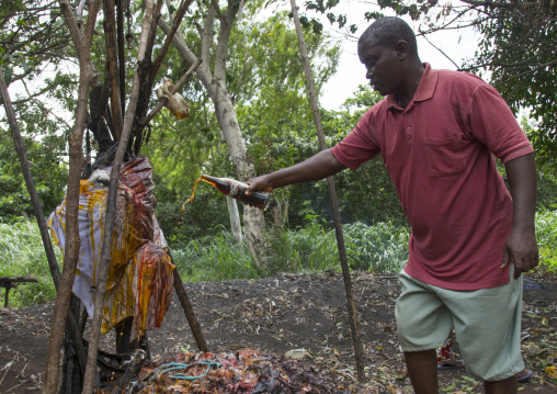 Benin, West Africa, Dankoly, a man putting coca cola on a voodoo shrine as offerings to the spirits