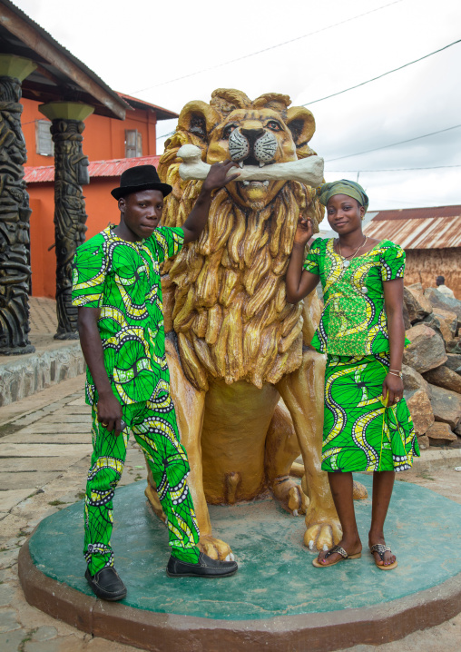 Benin, West Africa, Savalou, couple pausing in front of a lion statue in the royal palace sponsored by muammar gaddafi